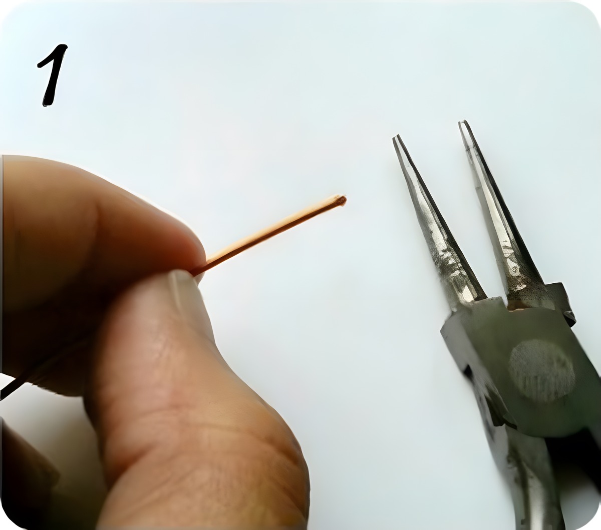 Holding the end of copper craft wire next to round-nose pliers to start making jump rings