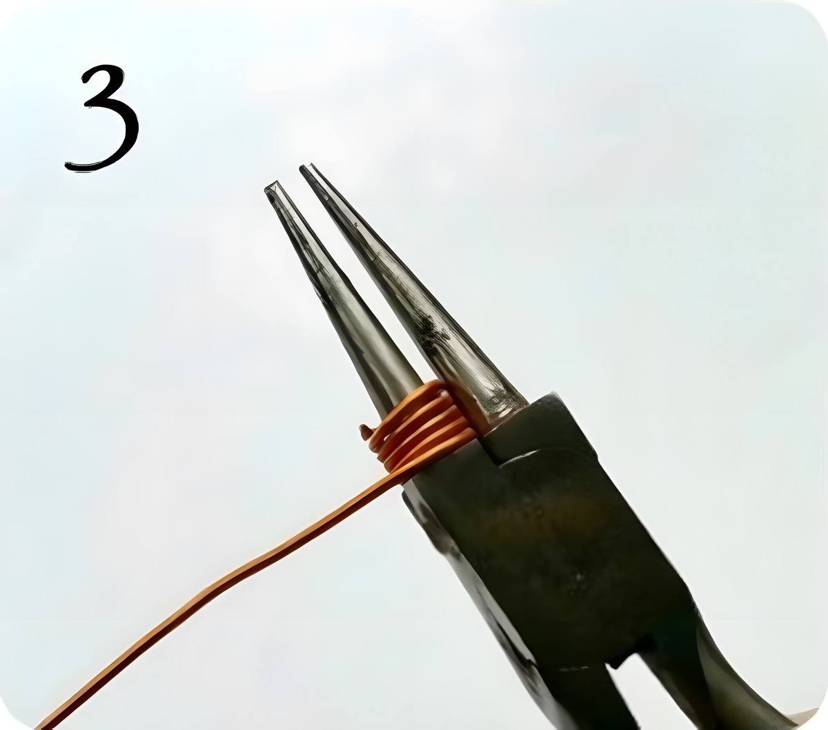 Copper wire partially coiled around the round-nose pliers forming a tight spiral