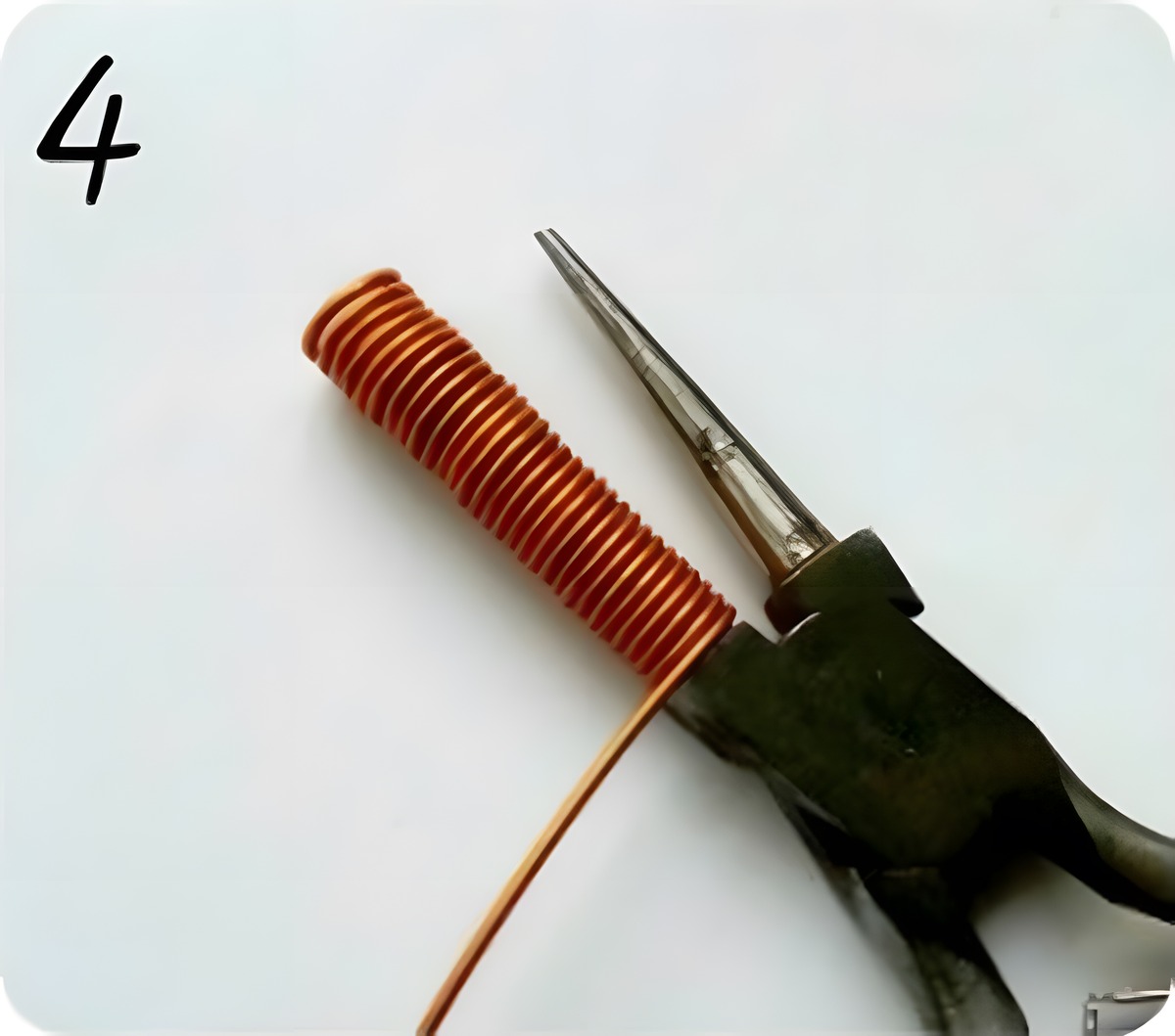 Full coil of copper craft wire wound tightly around the pliers barrel until full