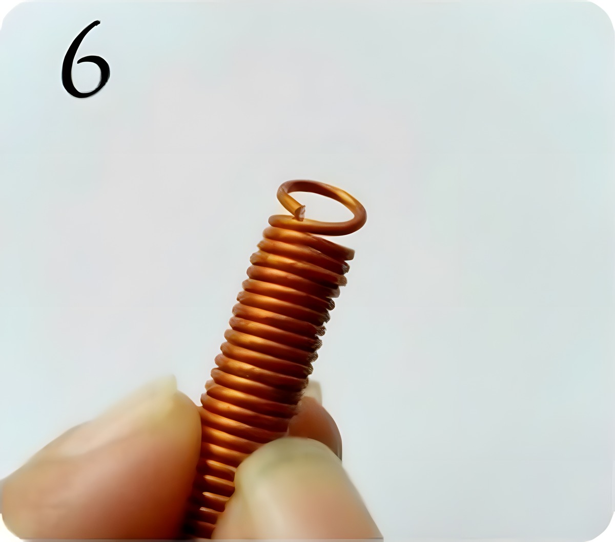 Holding the wire coil and pulling out one complete circle of wire to form a jump ring