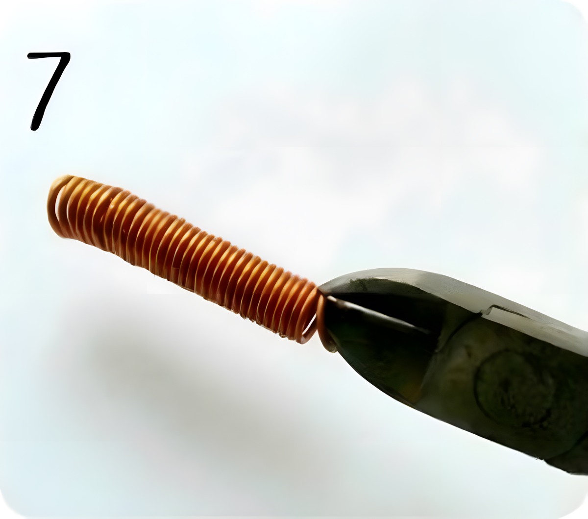 Cutting through one ring of the copper wire coil with cutting pliers to separate a jump ring