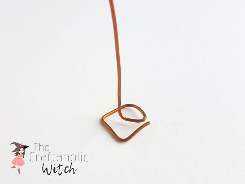 Wire bent into a small square with the stem angled upward for a wire picture holder