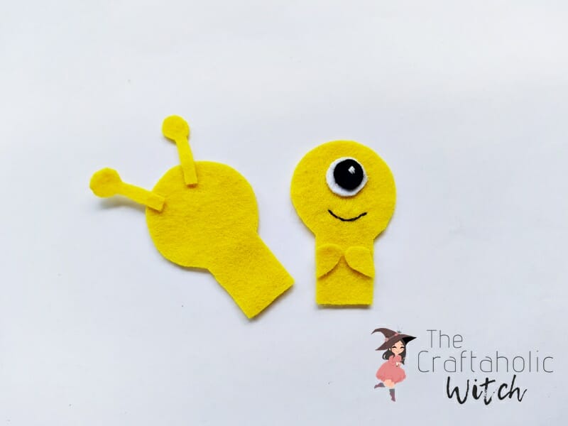 Layering the monster pencil topper pieces Front and back felt pieces of a monster pencil topper stacked together with the antennas sandwiched at the top