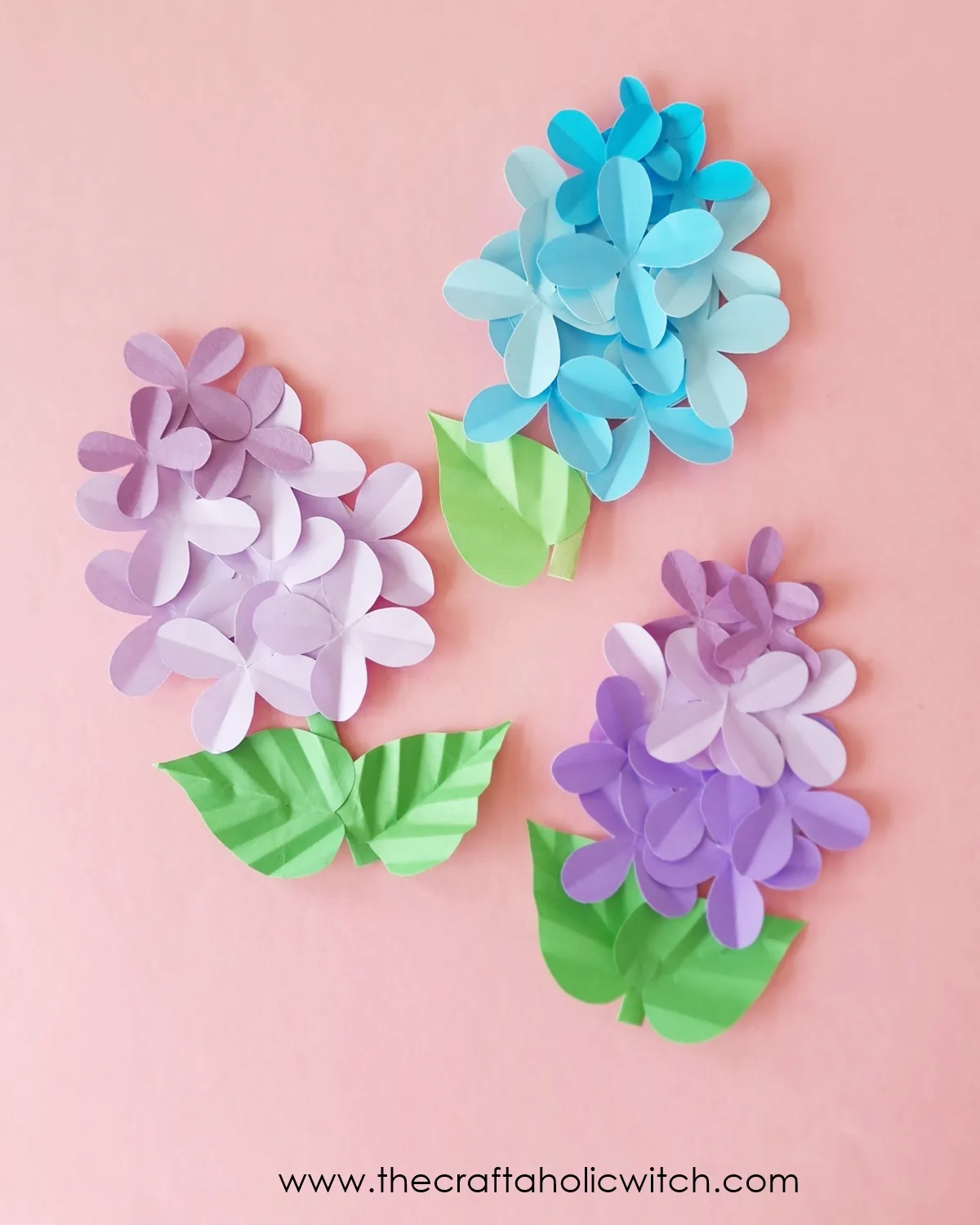 Paper lilac flower craft long image 1 Three finished paper lilac flowers arranged on a pink background