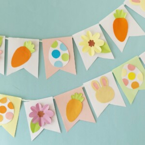 DIY Easter paper garland hanging on a wall with pastel cut-out shapes and string