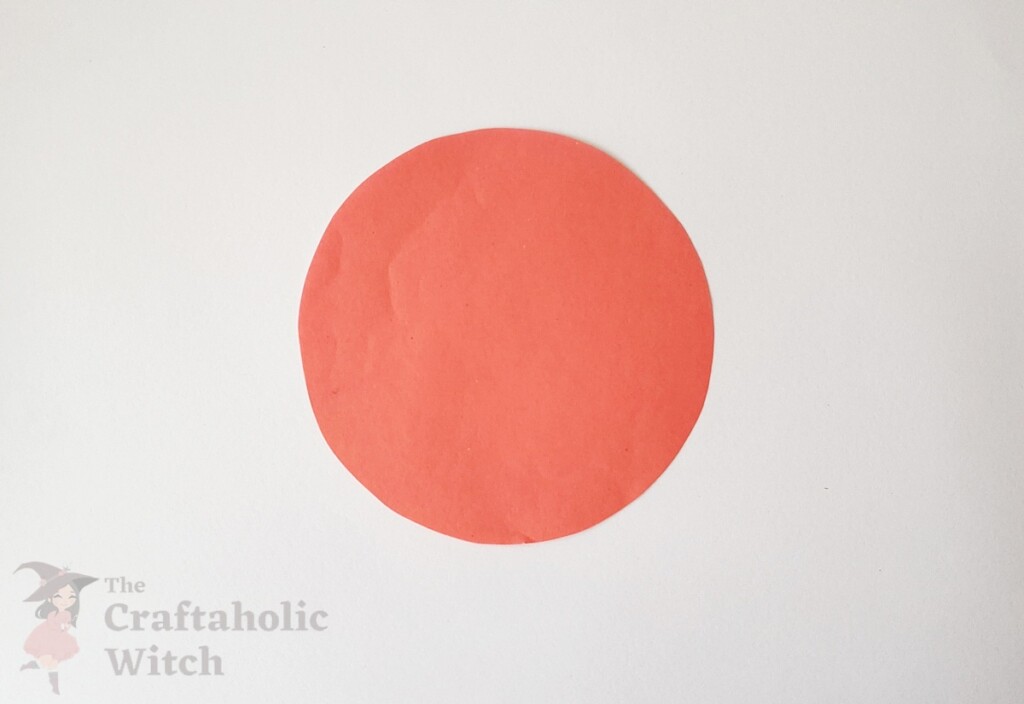 Hand tracing a circle on pink craft paper with pencil using a cup as template for Valentine's Day 3D paper heart craft