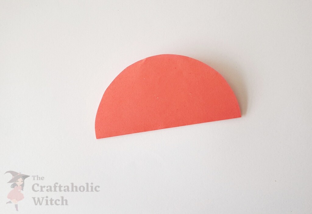 Pink paper circle folded in half showing sharp crease line for 3D Valentine's Day paper heart folding tutorial