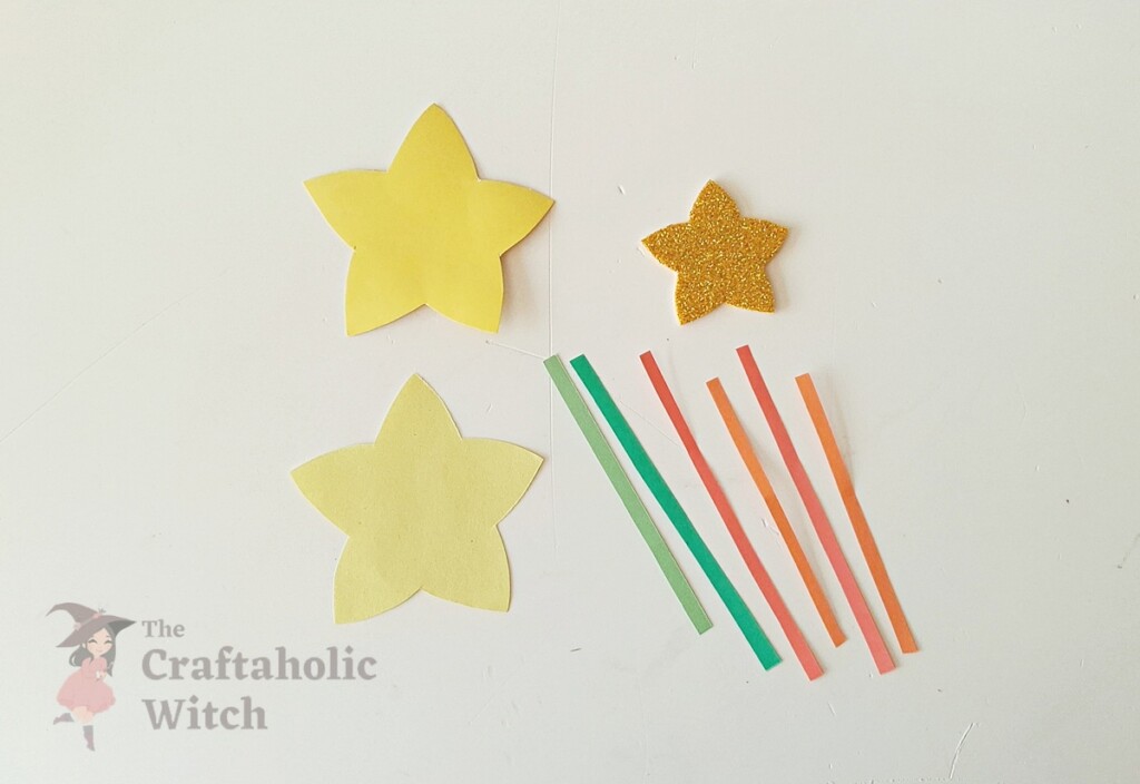 Traced star patterns and paper strips cut out on craft paper for star wand pencil topper