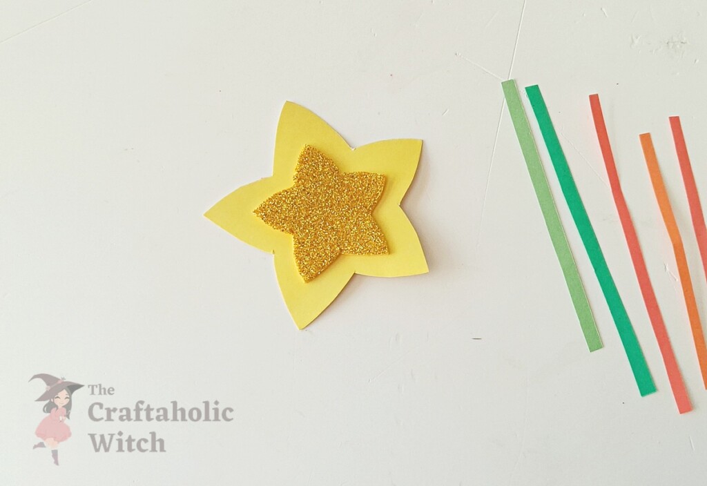 Small glitter star glued to center of large cardstock star for pencil topper craft