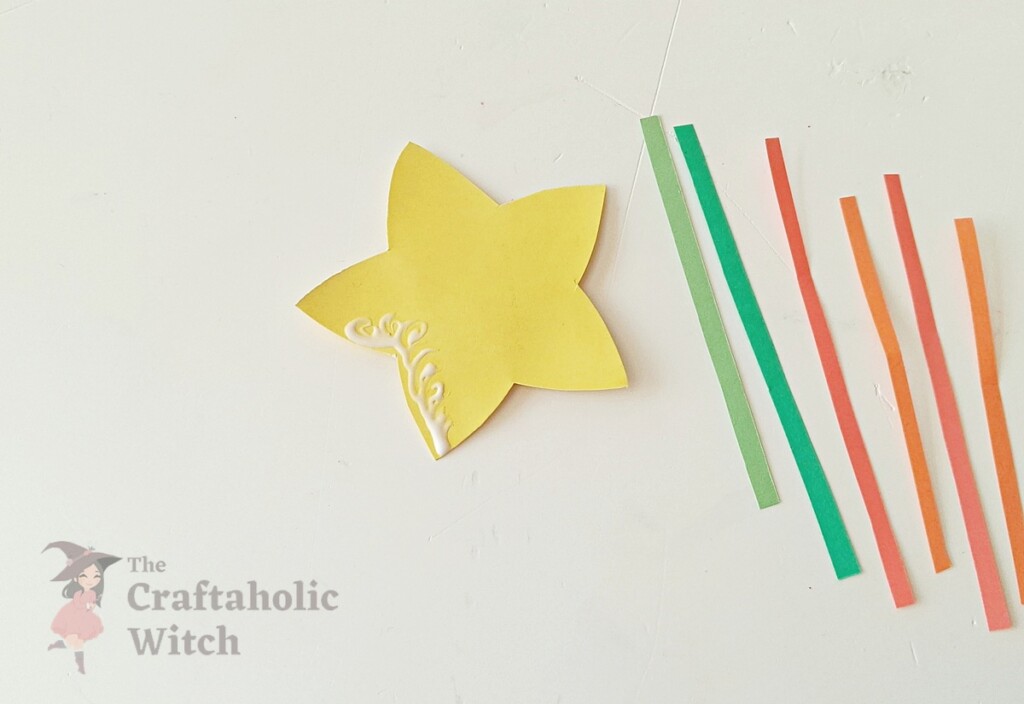 Back of paper star showing glue applied to two opposite star points for pencil topper assembly