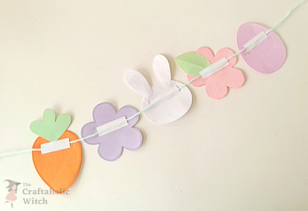 All paper garland pieces with yarn secured by glued paper strips on the back