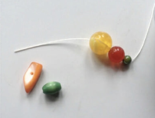 Adding faux pearls onto elastic thread to build the mixed beaded bracelet band around the accent beads