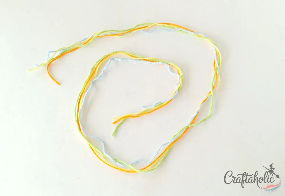 Four colors of yarn cut to length for a braided friendship bracelet