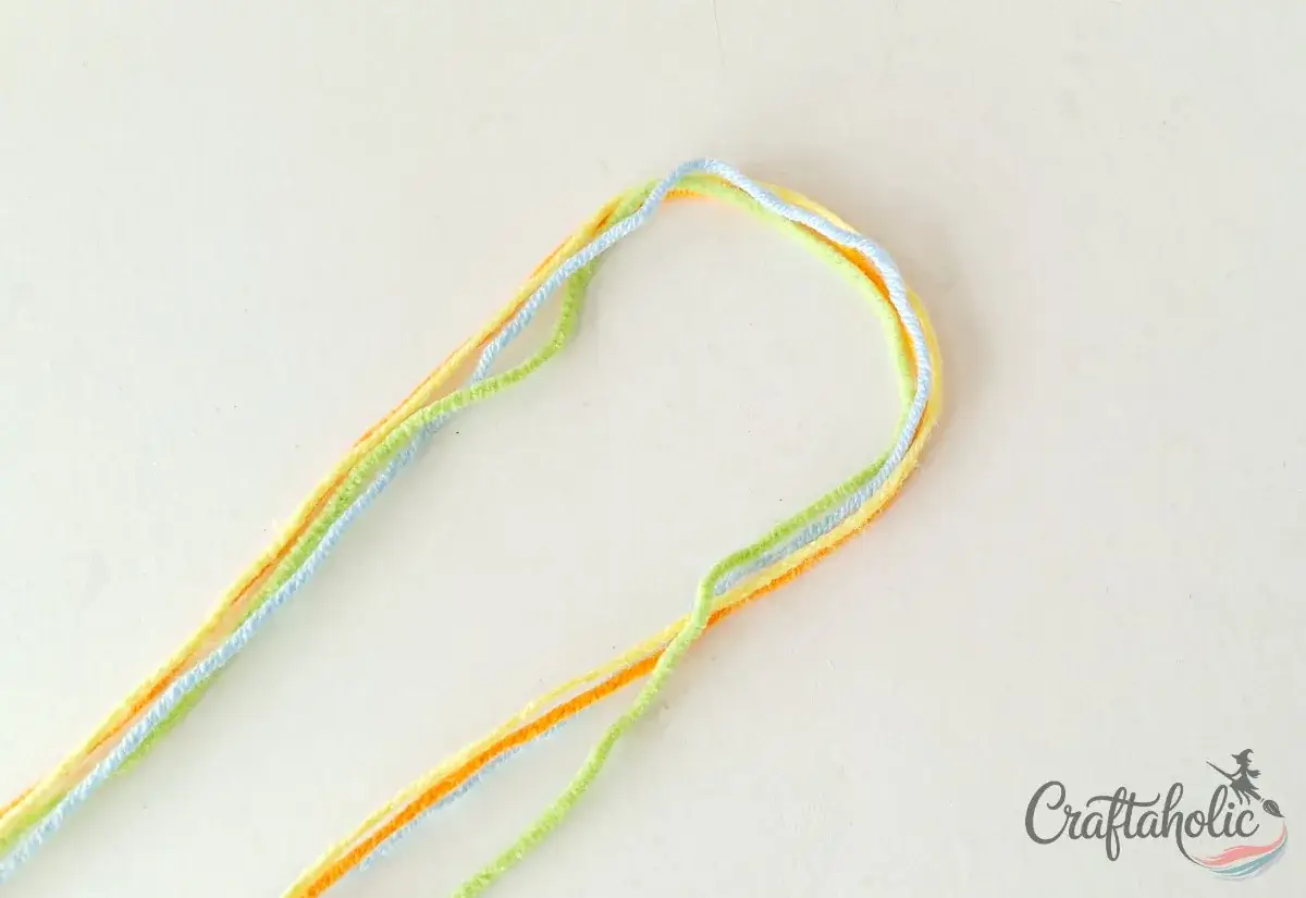 Folding the four yarn strands in half to start the friendship bracelet