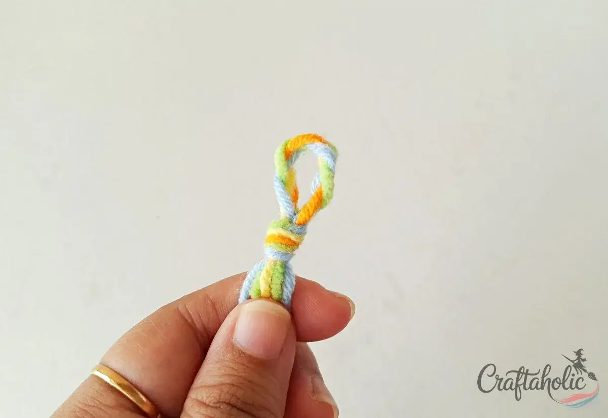 Tying a knot to secure the loop of the braided friendship bracelet