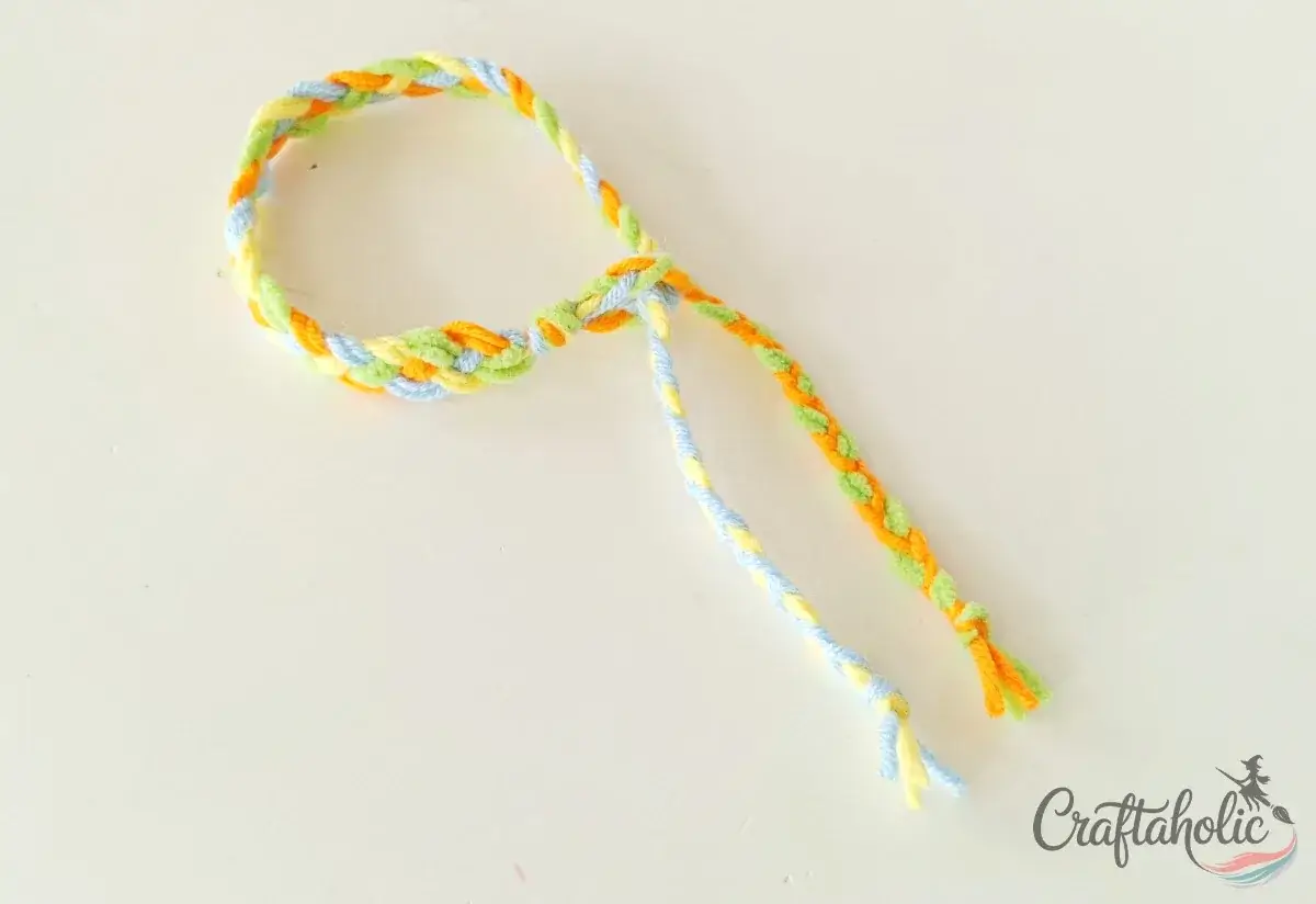 Inserting a braided tie through the loop to close the bracelet