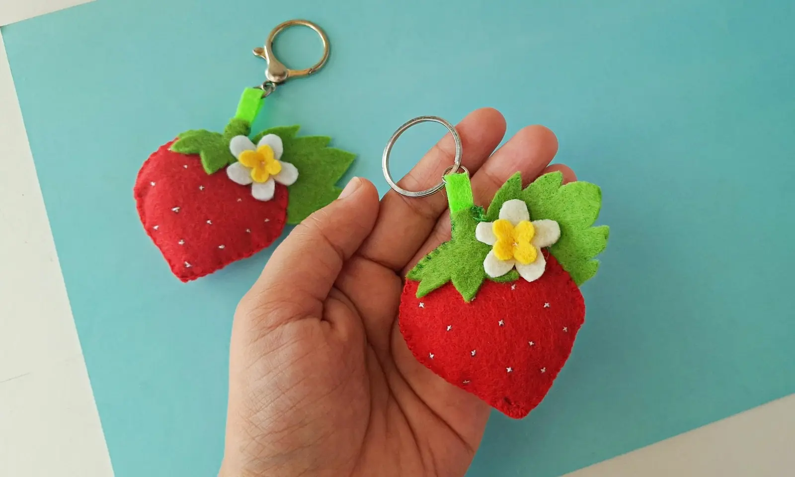 Finished felt strawberry keychains on a blue background