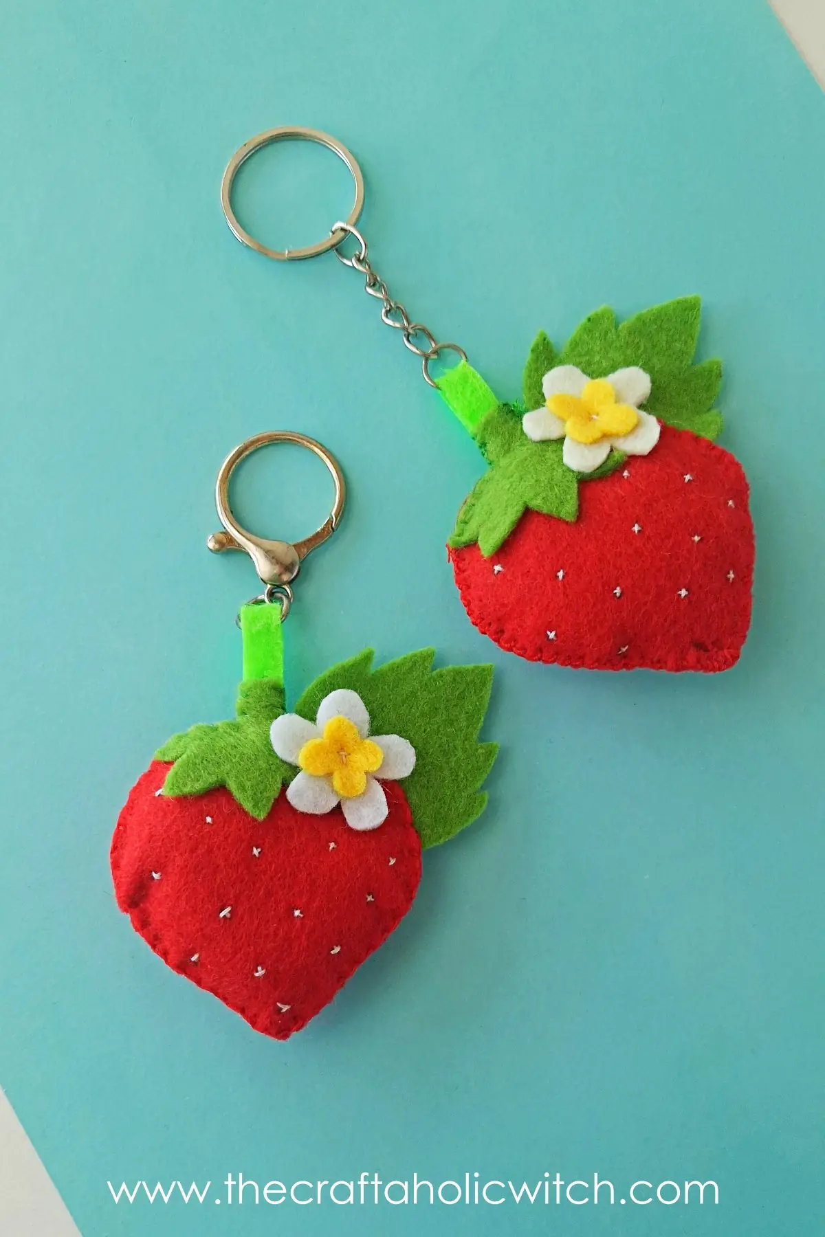 Two finished felt strawberry keychains styled for a tall image