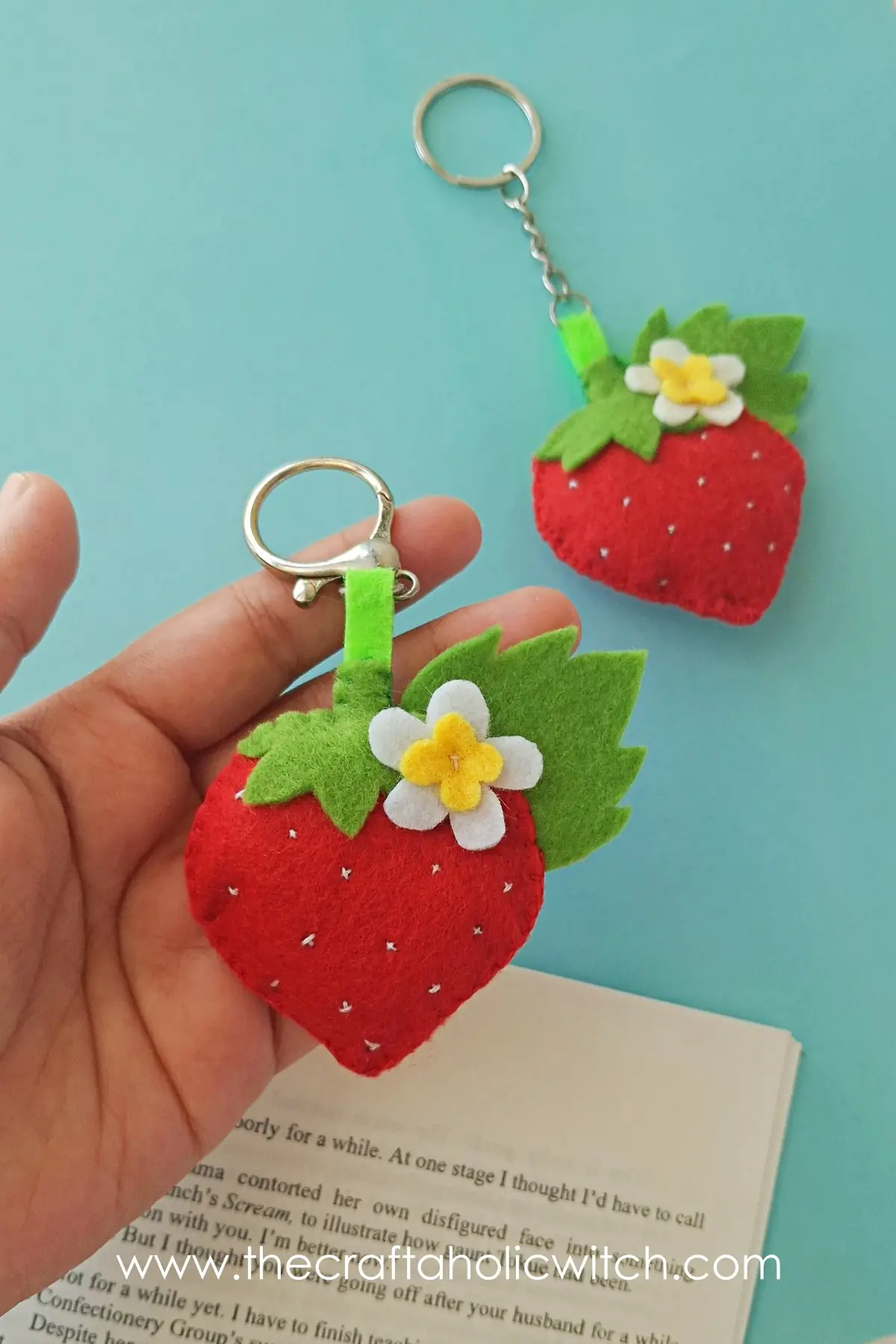 Close view of two felt strawberry keychains with rings attached