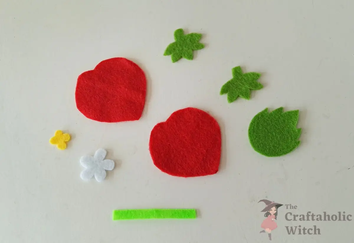 Cut felt pieces for the strawberry keychain laid out before sewing
