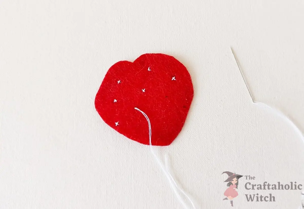 White seed stitches sewn across the front strawberry felt piece