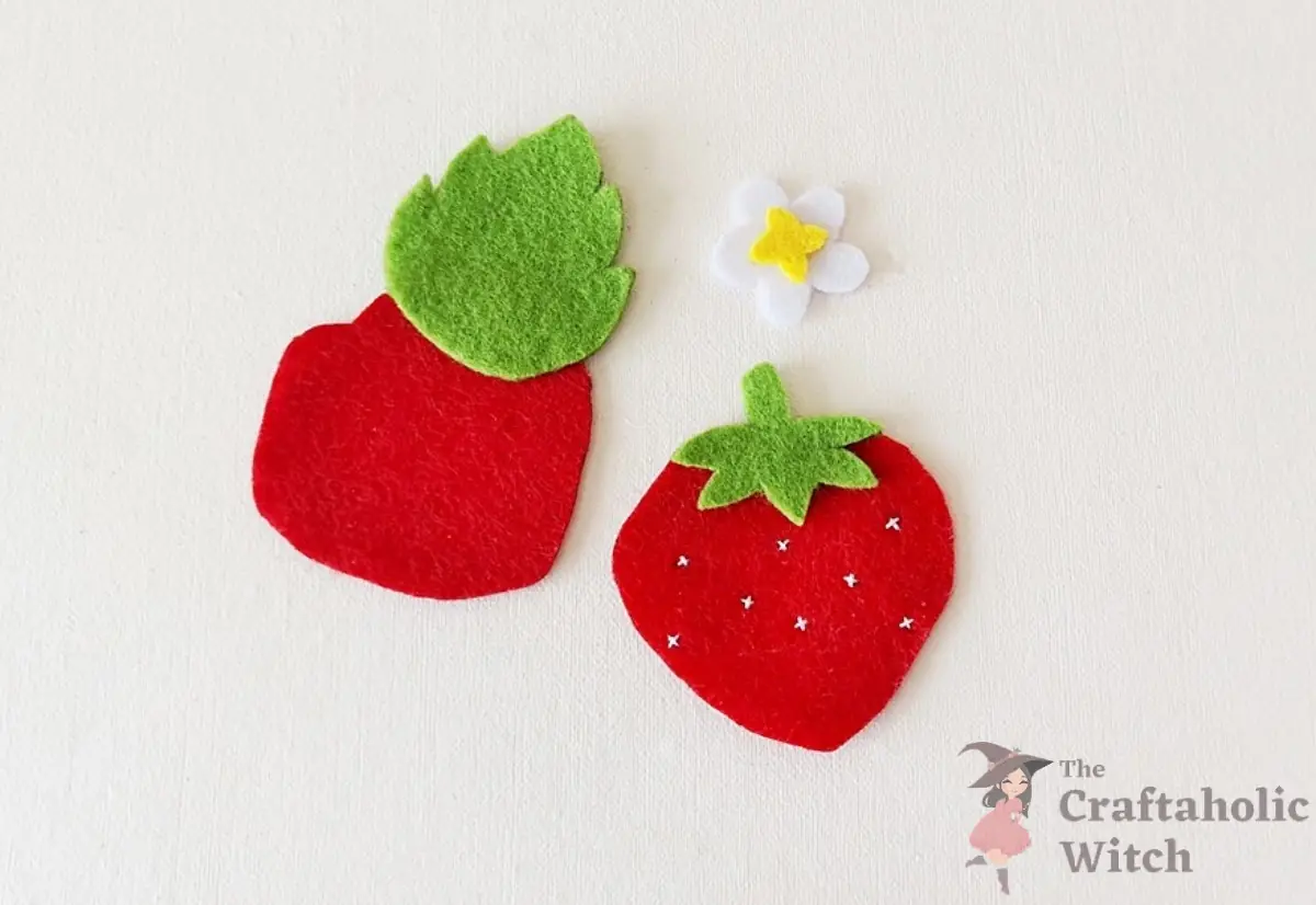 Felt flower, tops, and leaf arranged on the strawberry pieces before assembly