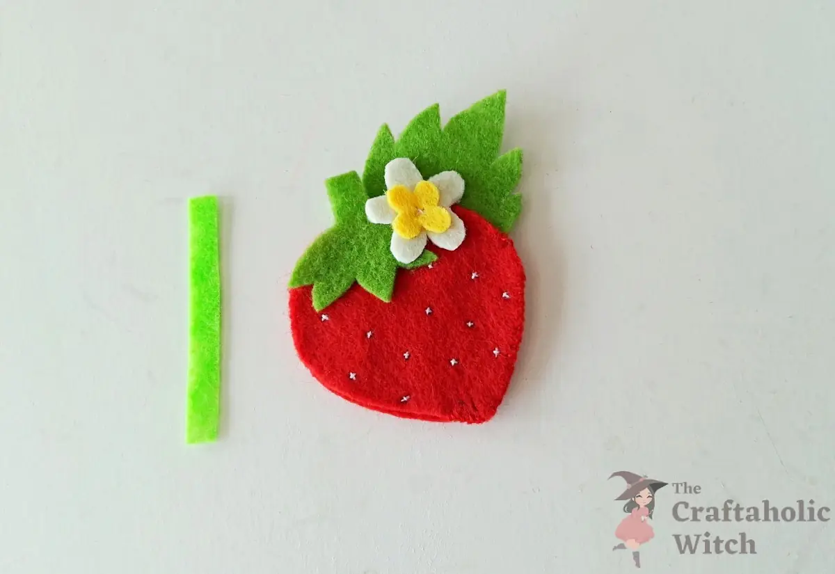 Flower attached at the top of the strawberry with the felt loop strip ready beside it
