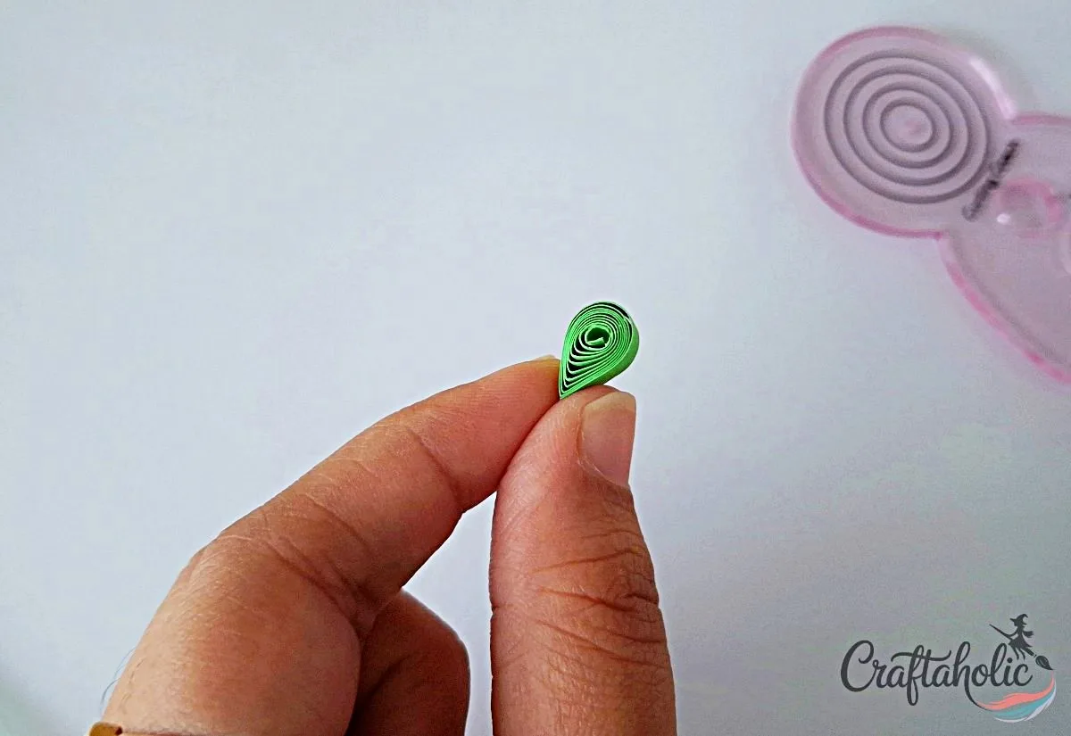 Press the coil into a teardrop Pressing a green loose coil into a teardrop shape for a quilled leaf