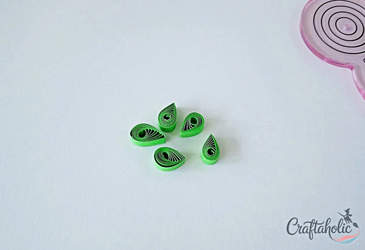 Prepare more teardrop leaves Several green quilled teardrop leaf shapes glued and ready for the frame