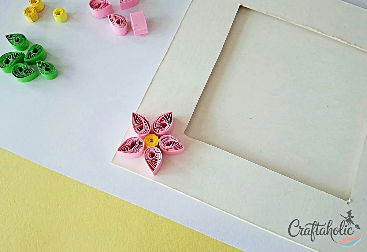 Create a flower shape Arranging quilled petals around a loose coil to form a flower on the frame