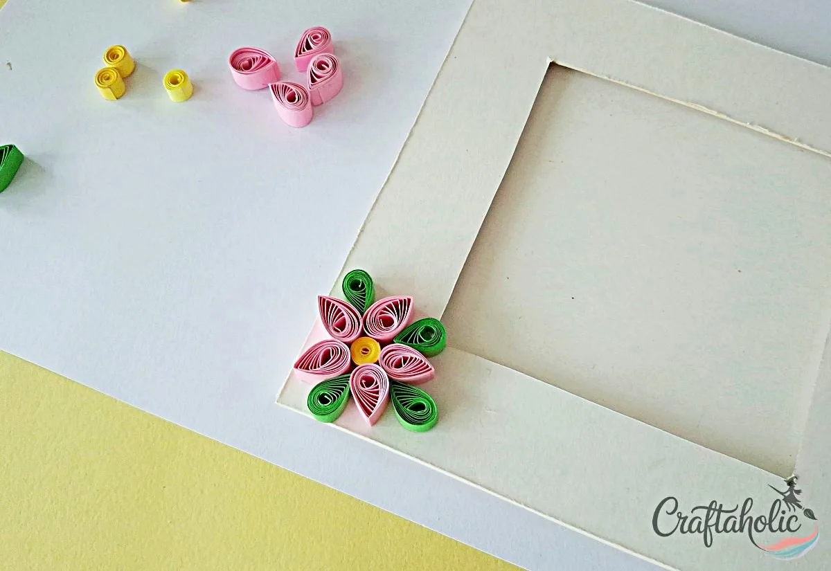 Add quilled leaves Adding quilled leaf shapes next to the flower on the photo frame