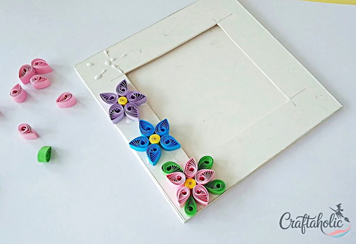 Continue adding quilled flowers Adding more quilled flower shapes to the photo frame with small gaps between them