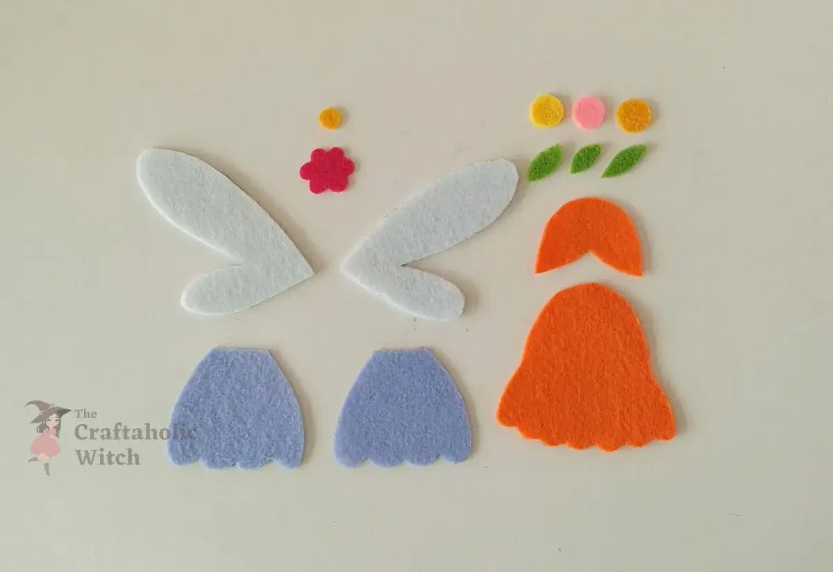 Tracing and cutting spoon fairy felt template shapes Tracing the spoon fairy template pieces onto colored felt sheets to cut out the hair, skirt, wings, and flower crown