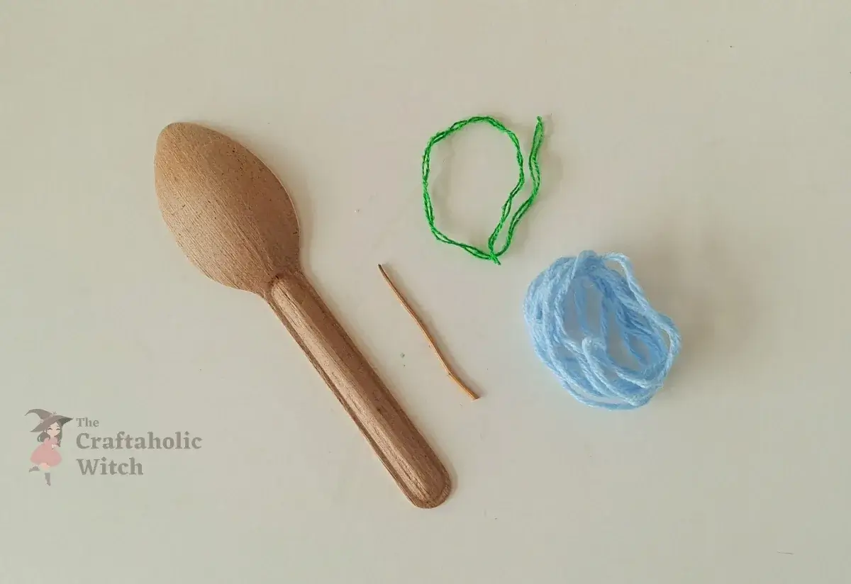 Selecting spoon, stick, and yarn for the spoon fairy Fiber spoon, small stick, and two yarn colors laid out to select materials for the recycled spoon fairy craft