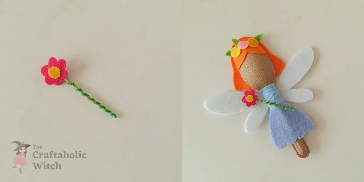 Attaching felt flower topper to wand and placing it with the spoon fairy Gluing the assembled felt flower topper to the yarn-wrapped wand stick and positioning the wand at the spoon fairy's side