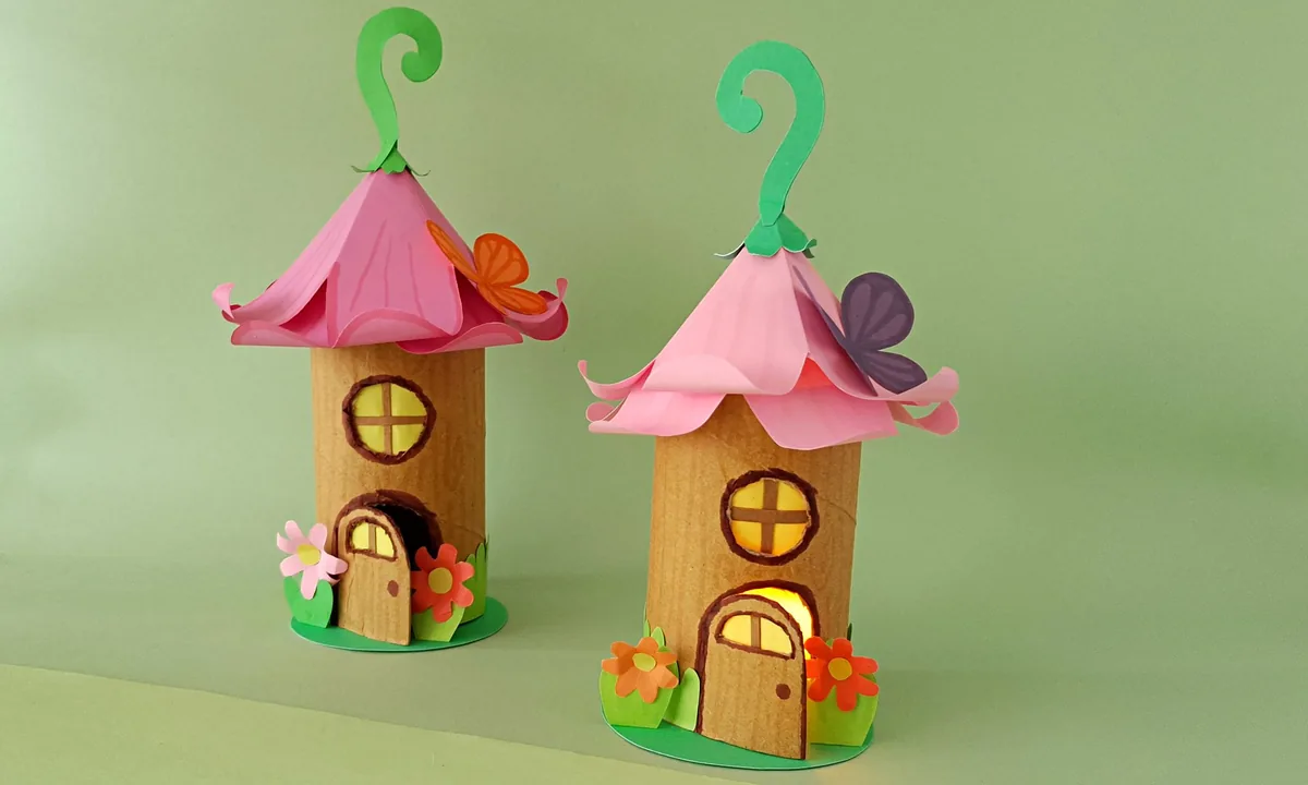 Two finished toilet paper roll fairy house lanterns with pink flower roofs