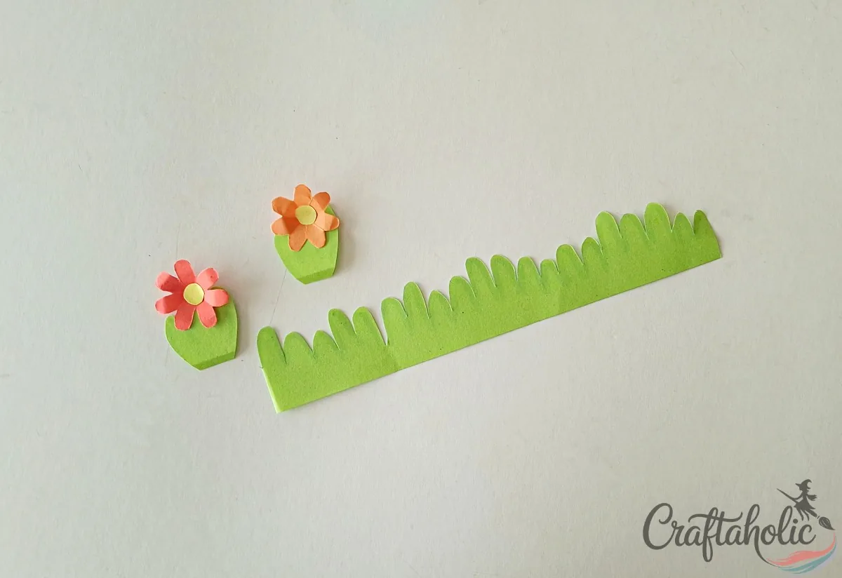 Gluing round centers onto the small flowers and attaching them to the grass cutouts