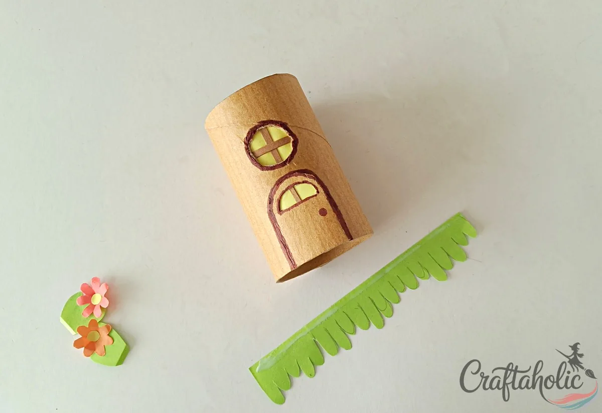 Covering the window and door holes and wrapping grass around the tube fairy house
