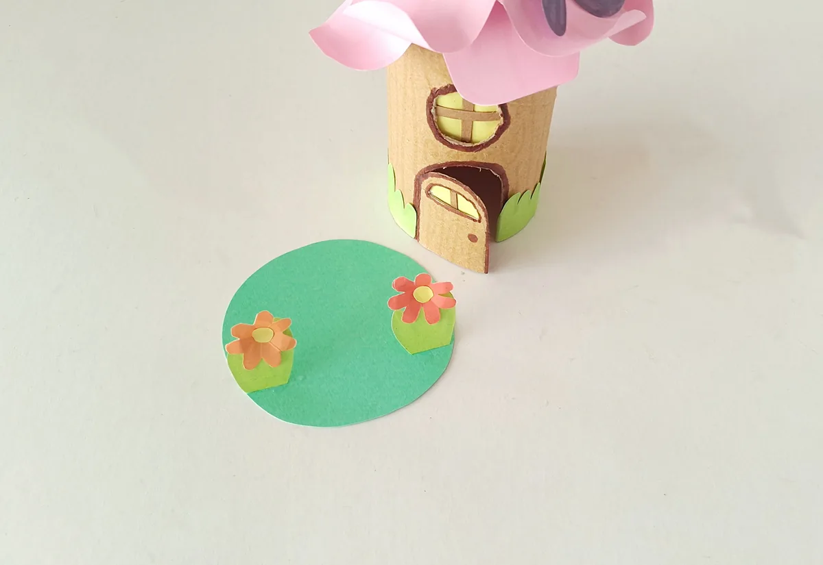 Gluing the small grass flowers to both sides of the fairy house base