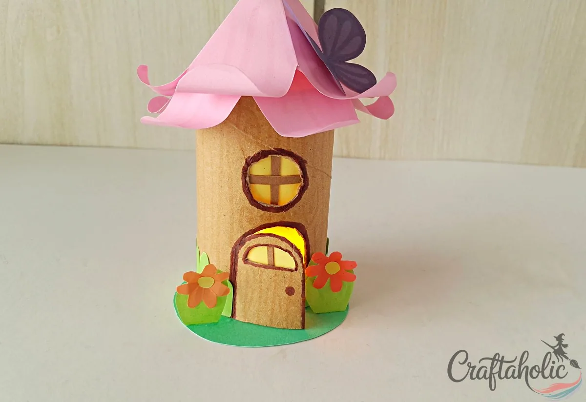 Placing the toilet paper roll fairy house over the LED candle to finish the lantern
