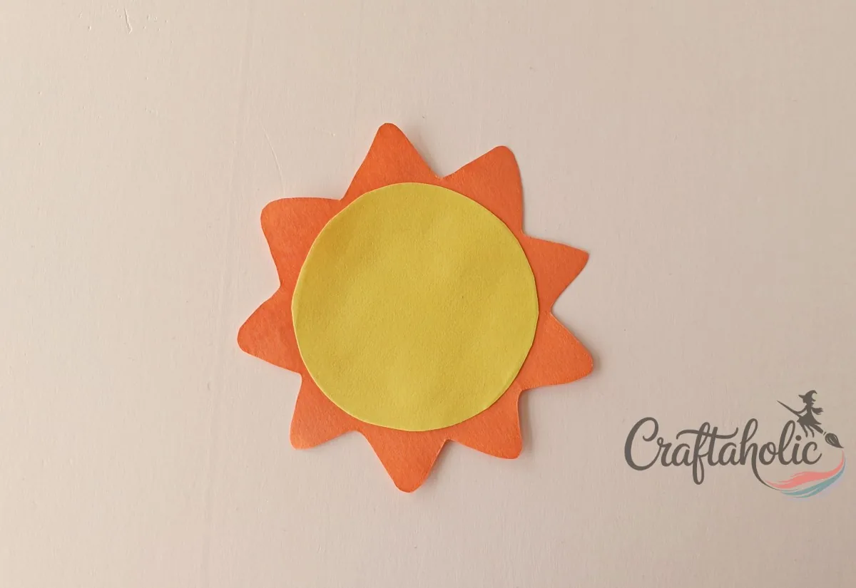 Gluing the paper sun pieces together Gluing a paper circle onto a zigzag bordered cutout to craft the paper sun banner