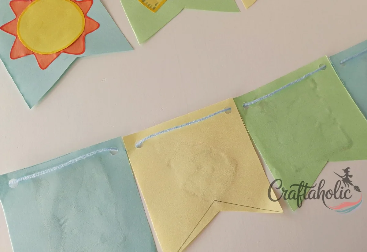 Threading string through the bunting flags Threading yarn through the punched holes to string the paper buntings into a garland