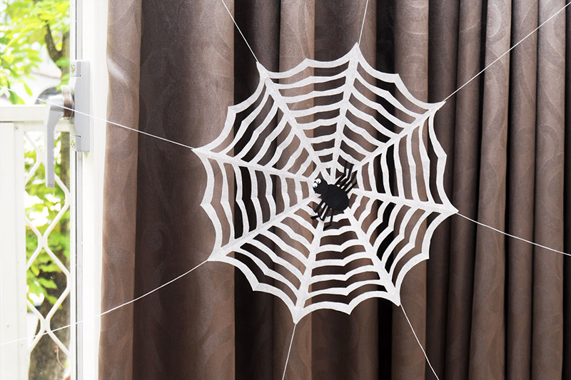 20 Easy Halloween Paper Crafts for Kids to Make at Home 12 Cut paper spider web craft: white folded and cut paper spider web with a paper spider