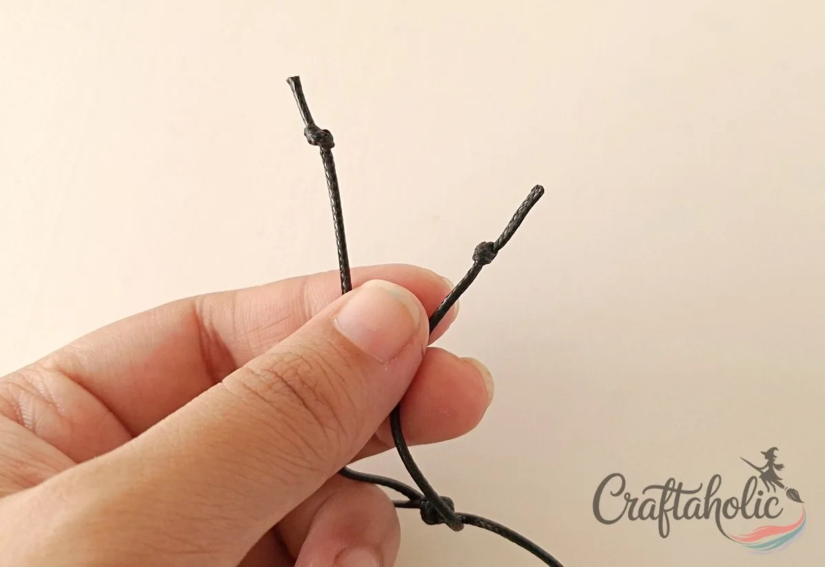 Knotting the open cord ends Tying knots at both open ends to secure the bracelet closure