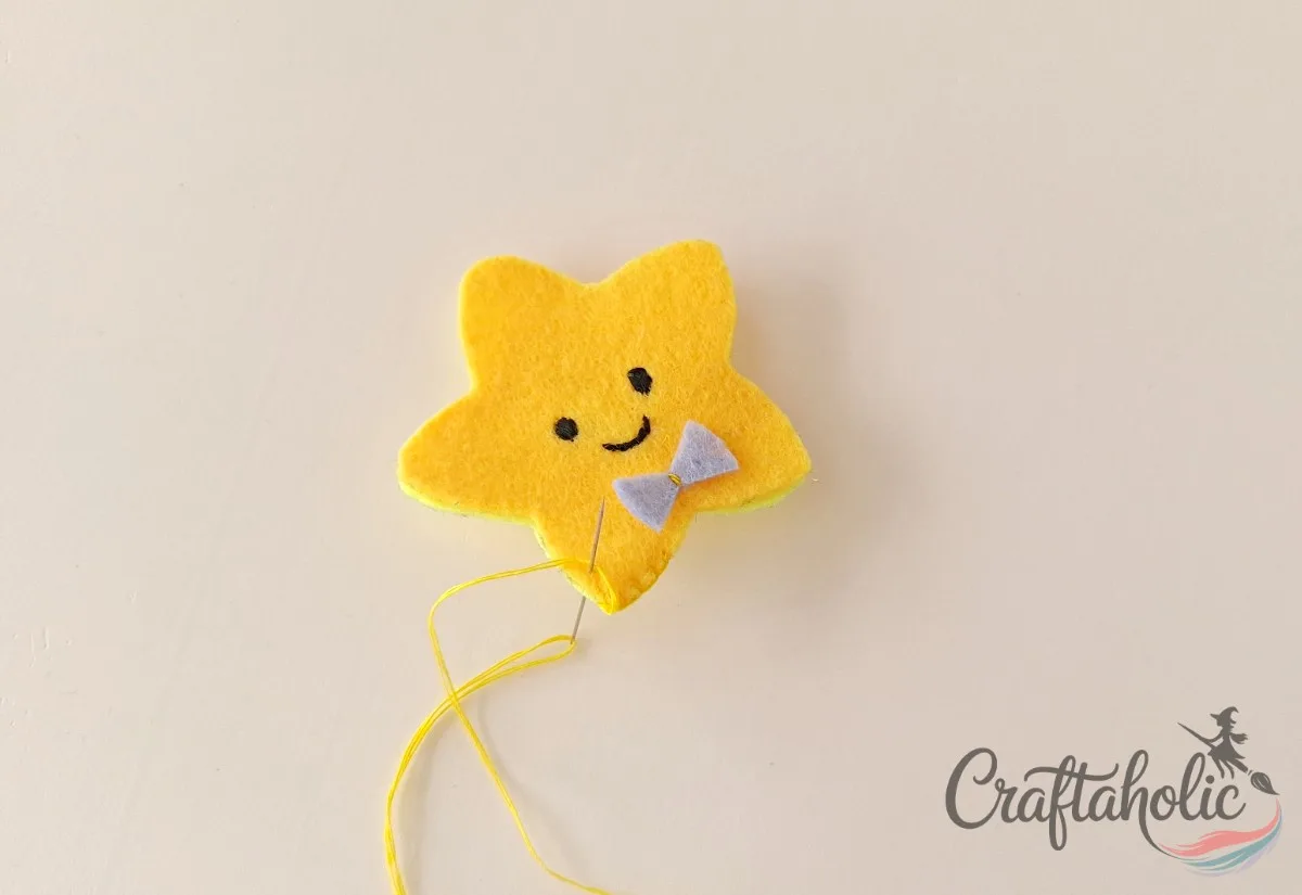 Blanket stitching around the edge of the felt star pencil topper with the bow tacked in place