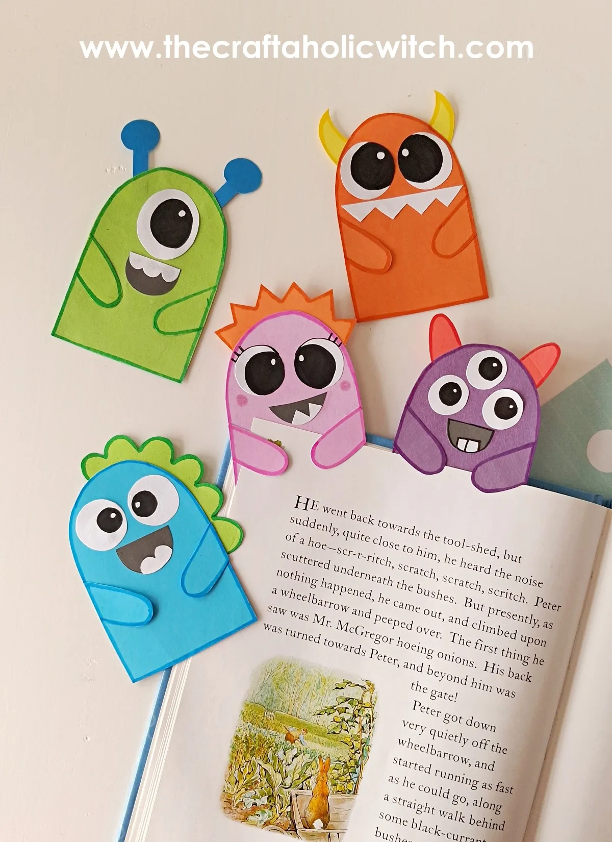DIY Monster Bookmarks (Easy Paper Craft for Kids) 2 Four finished paper monster bookmarks with horns, eyes, and antennae clipped onto a book
