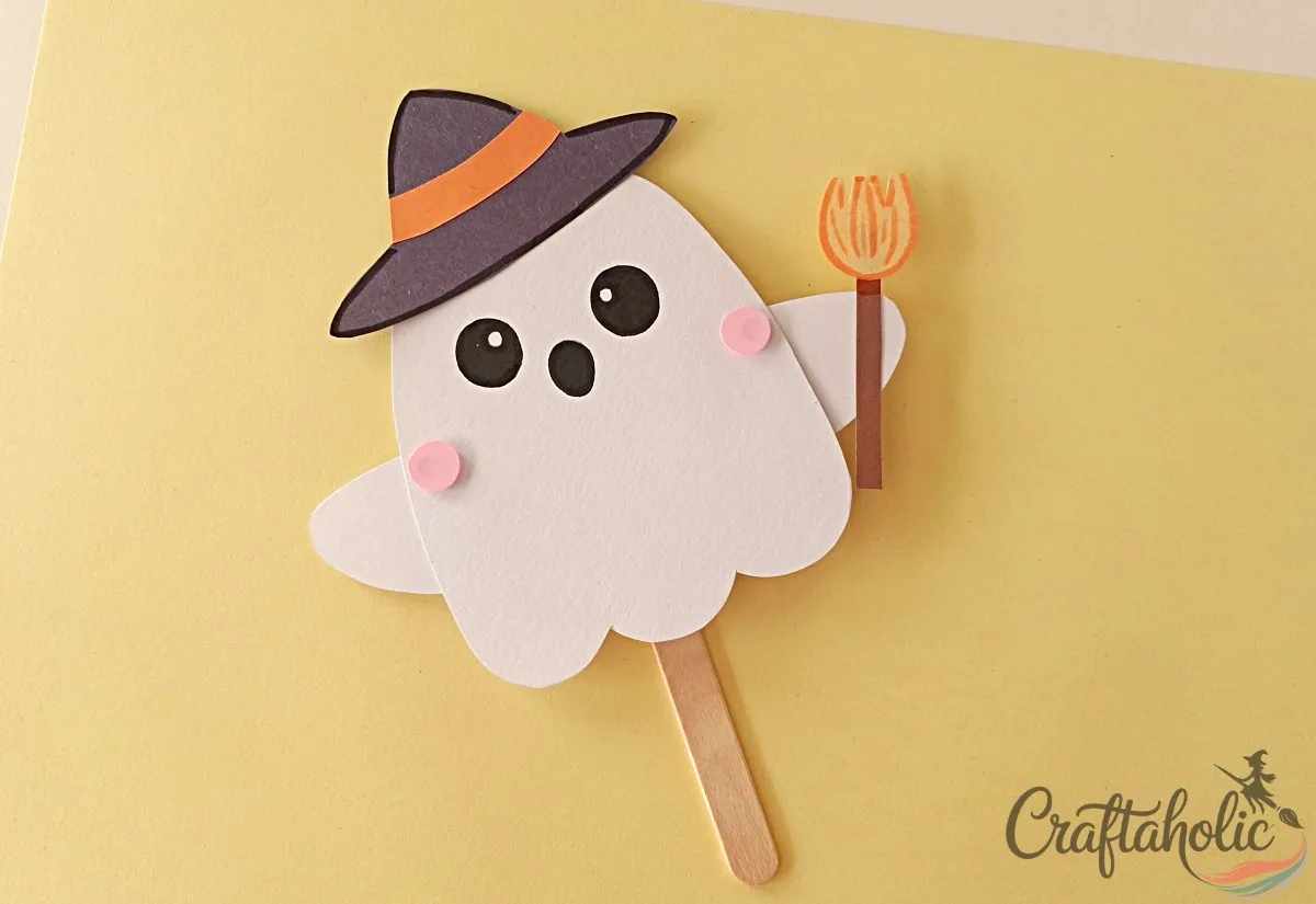 Gluing on the hat and broomstick Gluing the witch hat and broomstick onto the finished ghost puppet