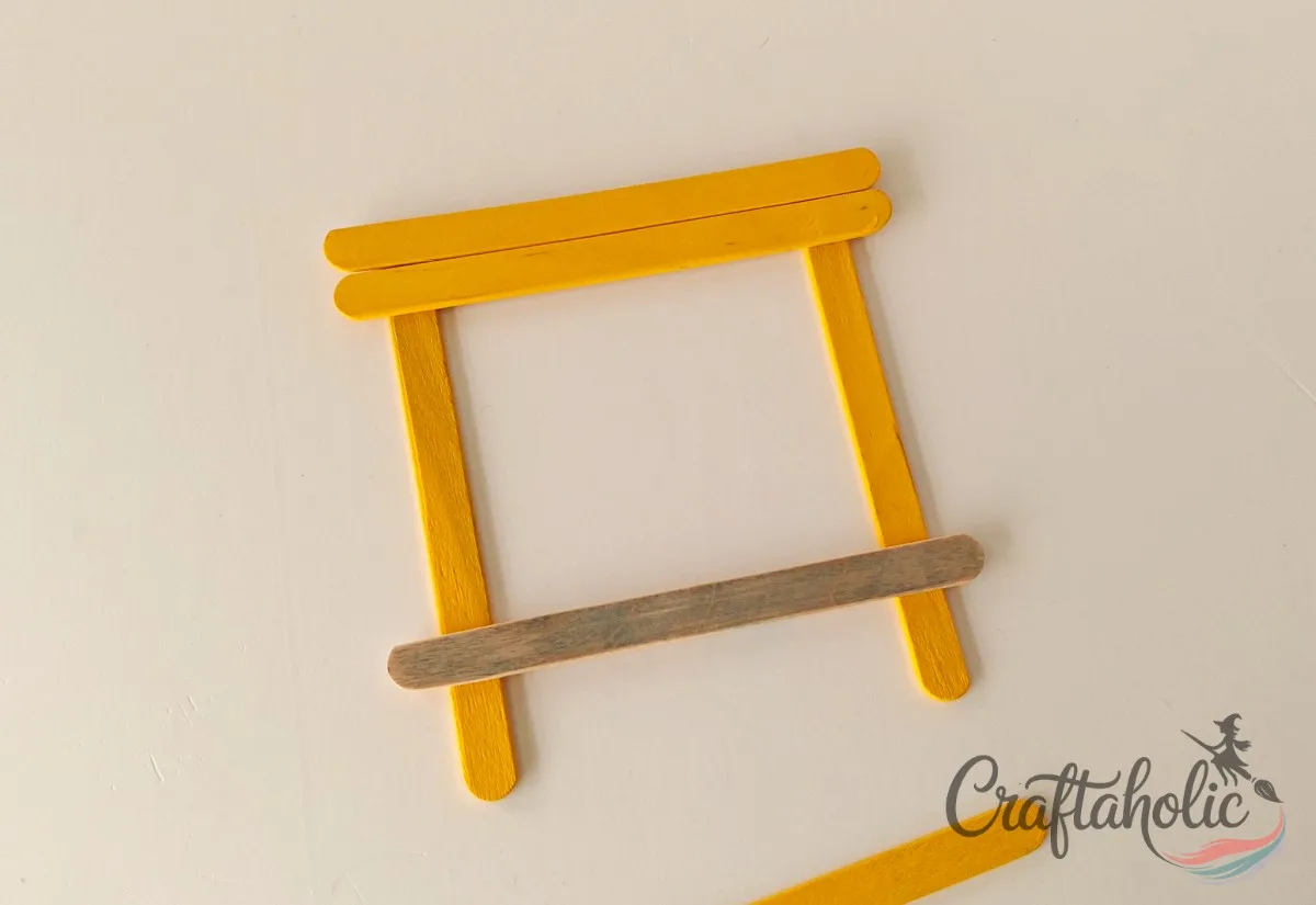 Adding the grey popsicle stick Adding another yellow stick and the grey popsicle stick to shape the bus
