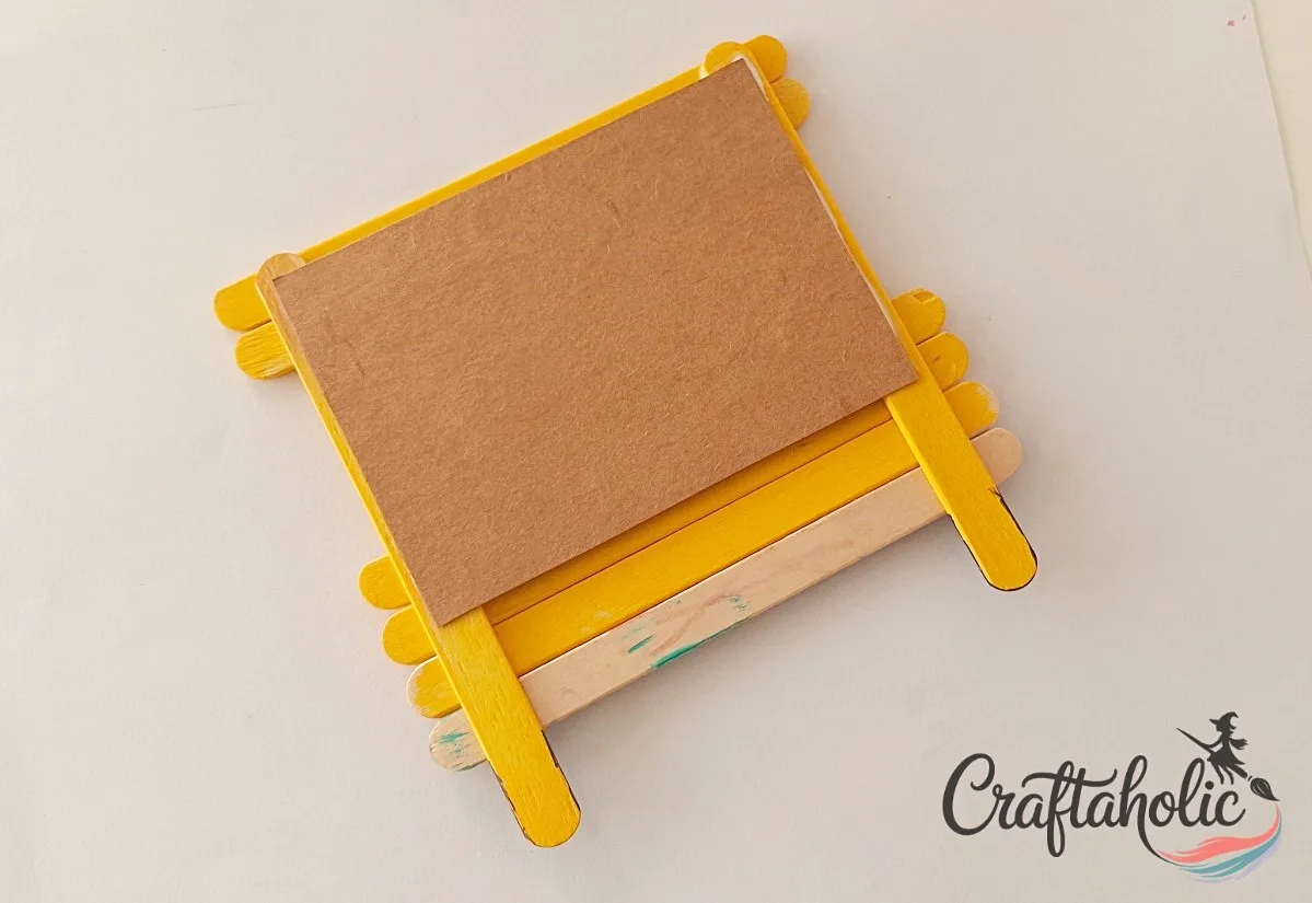 Gluing the cardstock backing Gluing a cardstock paper backing inside the popsicle stick school bus frame