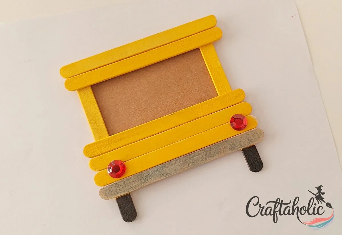 Adding rhinestone headlights Gluing red rhinestones onto the popsicle stick bus as headlights